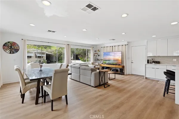 a kitchen with stainless steel appliances granite countertop a dining table chairs stove and white cabinets