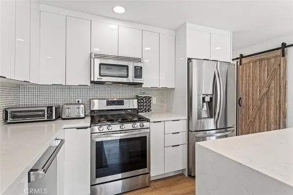 a kitchen with stainless steel appliances white cabinets and a stove top oven