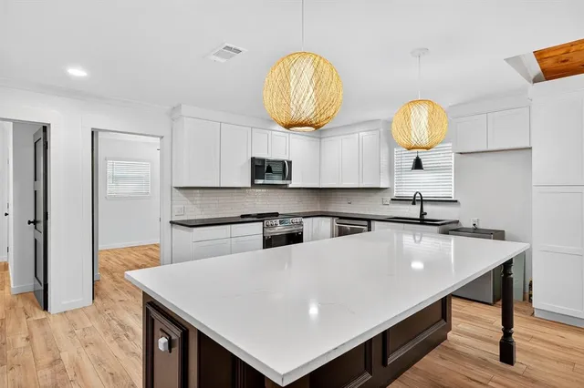 a large kitchen with stainless steel appliances granite countertop a sink and dishwasher a stove top oven with wooden floor