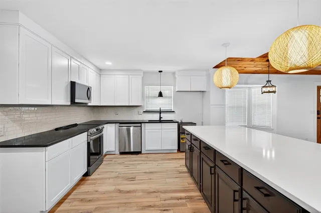 a kitchen with granite countertop white cabinets sink and stainless steel appliances