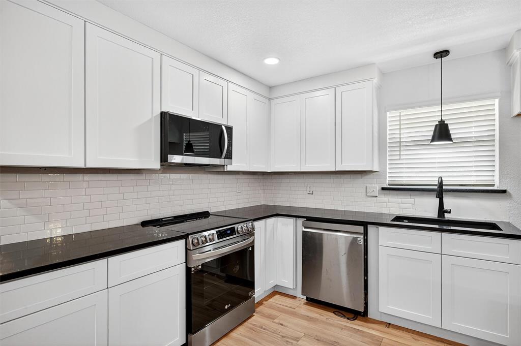621 Craft Road Bells, TX 75414 - Photo 13 of 40 a kitchen with granite countertop white cabinets sink and stainless steel appliances