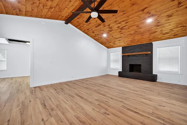 a kitchen with stainless steel appliances kitchen island granite countertop a refrigerator a sink dishwasher a stove and white countertops with wooden floor