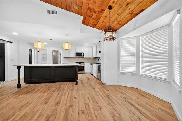 a kitchen with kitchen island granite countertop a sink a stove and a wooden floors