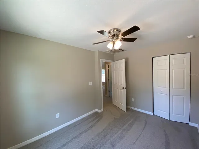 an empty room with closet and a chandelier fan