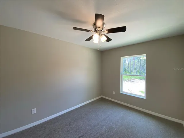 an empty room with a window and a fan