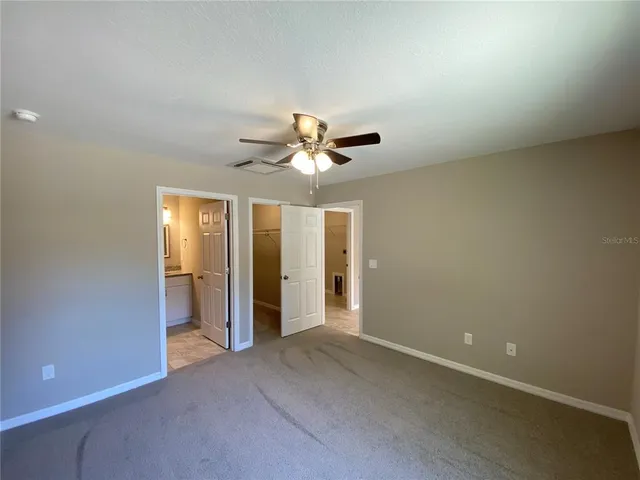 an empty room with closet and a ceiling fan