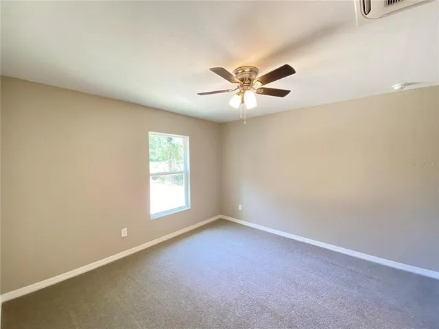 an empty room with a window and a fan