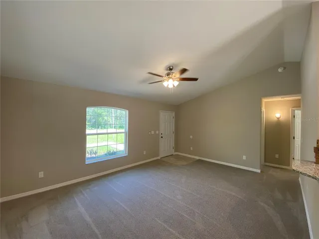 an empty room with windows and chandelier fan