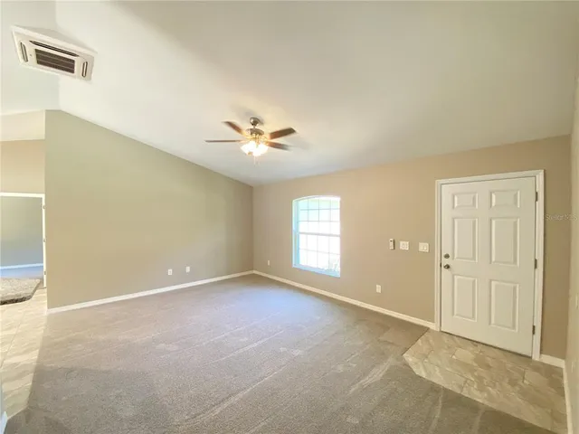 an empty room with windows and chandelier fan