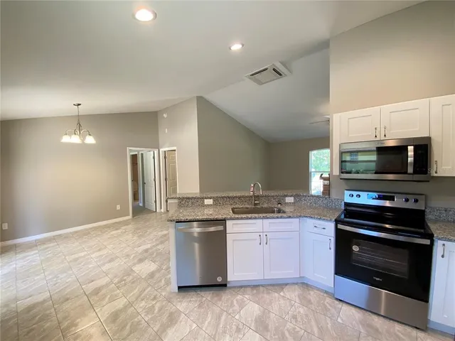 a kitchen with stainless steel appliances granite countertop a stove top oven a sink dishwasher and a refrigerator with wooden floor