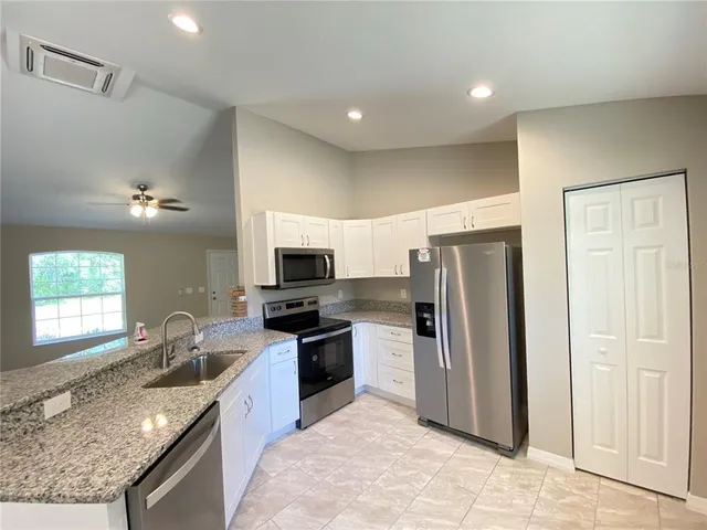 a kitchen with granite countertop a refrigerator stove and sink