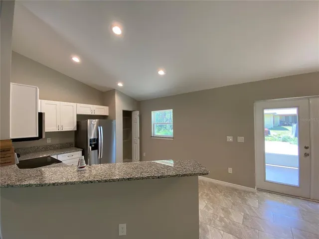 a view of a kitchen with granite countertop a sink and dishwasher with wooden floor