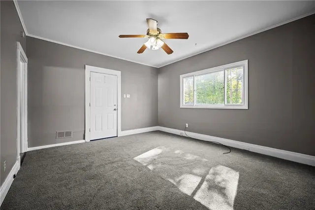 an empty room with windows and fan