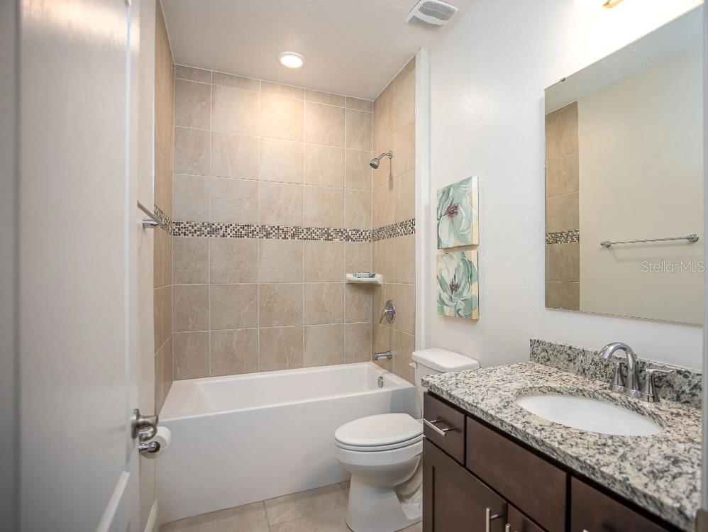 12899 Florida Avenue Astatula, FL 34705 - Photo 20 of 50 a bathroom with a granite countertop sink toilet mirror and bathtub