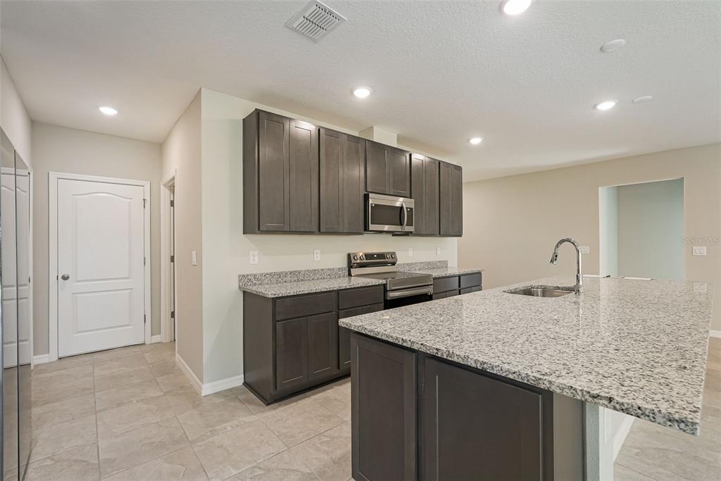 12899 Florida Avenue Astatula, FL 34705 - Photo 23 of 50 a kitchen with stainless steel appliances granite countertop a sink stove and refrigerator