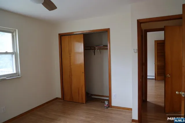 an empty room with wooden floor closet and windows