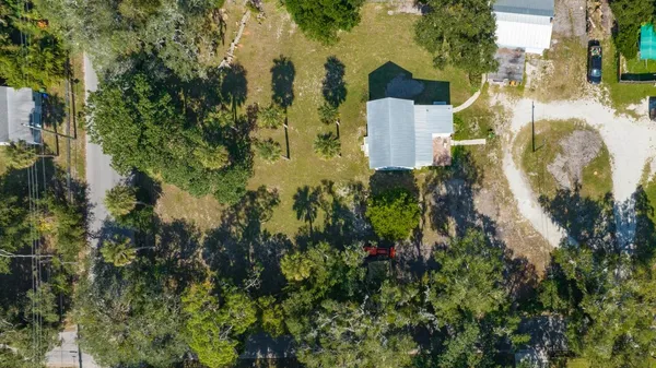 an aerial view of residential house with outdoor space and trees all around