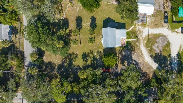 an aerial view of residential house with outdoor space and trees all around