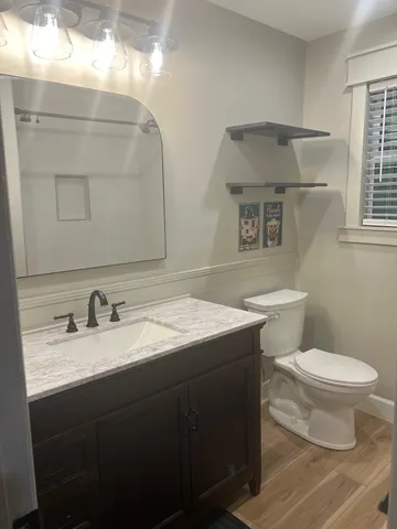 a bathroom with a granite countertop sink a toilet and a mirror