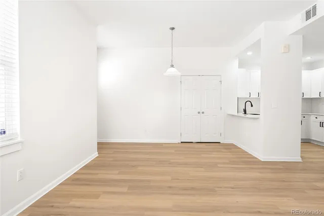 a view of an empty room with kitchen and a window