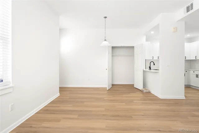 a view of an empty room with kitchen and a window