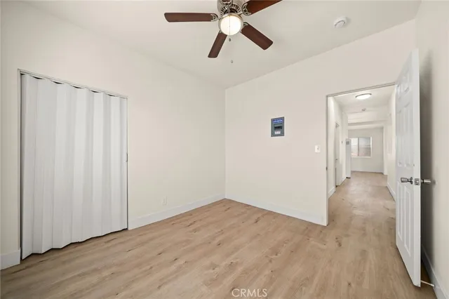 an empty room with wooden floor closet and ceiling fan