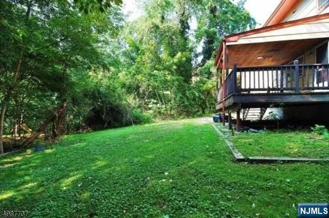 a backyard of a house with lots of plants and large tree