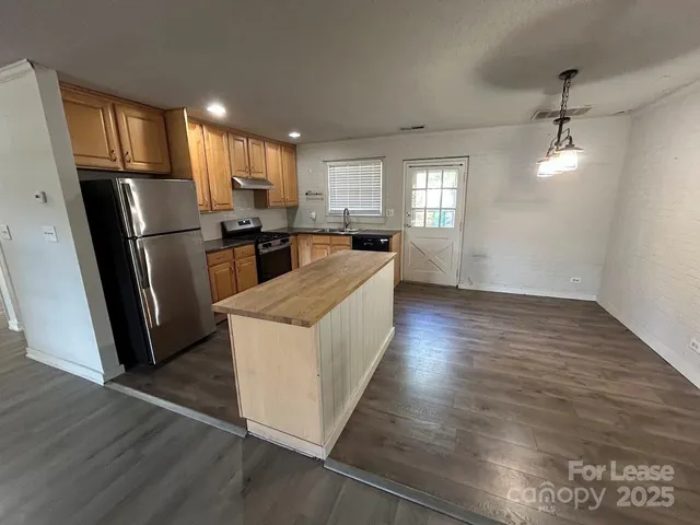 a kitchen with stainless steel appliances a refrigerator a sink a stove a microwave a center island and wooden floor