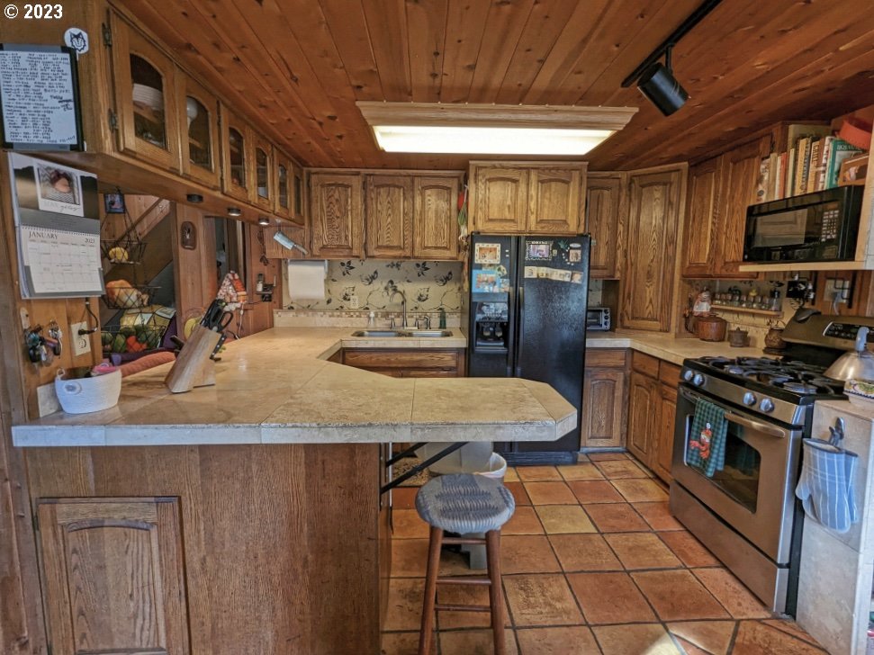 72769 Snowdon Road Rhododendron, OR 97049 - Photo 30 of 48 a kitchen with stainless steel appliances granite countertop a stove a sink dishwasher and a refrigerator with wooden cabinets