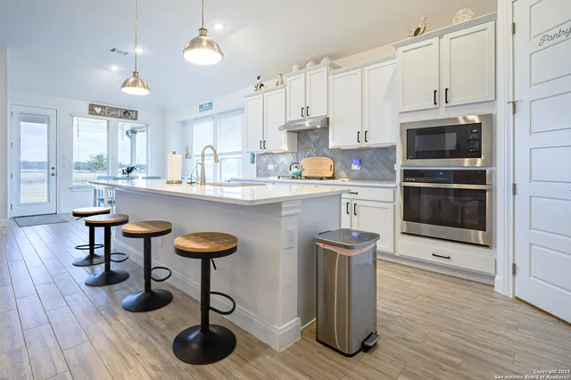 a kitchen with stainless steel appliances granite countertop a stove top oven a sink dishwasher and cabinets with wooden floor