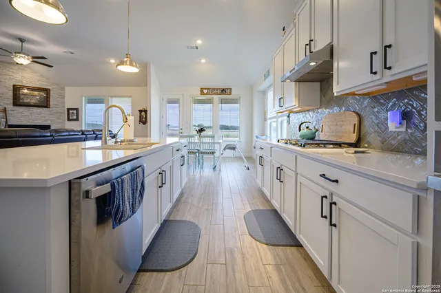a kitchen with stainless steel appliances granite countertop a stove a sink dishwasher and cabinets with wooden floor