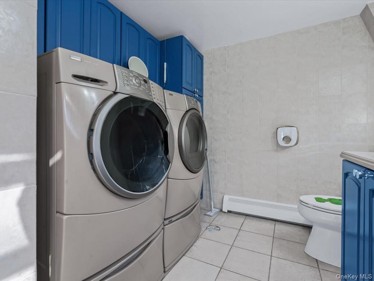 217-32 Corbett Road Queens, NY 11361 - Photo 17 of 25 Washroom with light tile patterned floors, baseboard heating, separate washer and dryer, and tile walls