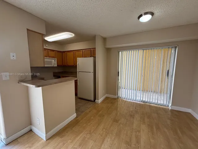 a view of a kitchen with a sink refrigerator and wooden floor