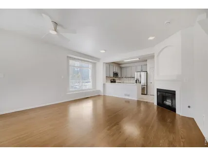 a view of empty room with wooden floor and kitchen view