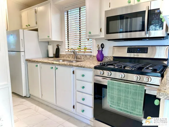 a kitchen with stainless steel appliances granite countertop a stove a microwave and a refrigerator