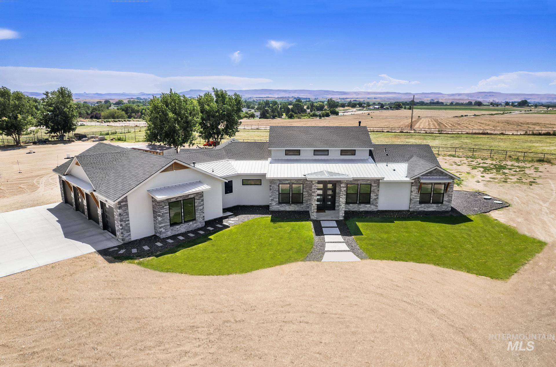 27114 Lower Pleasant Ridge Road Wilder, ID 83676 - Photo 2 of 48 Modern farmhouse with stone siding, concrete driveway, a rural view, and an attached garage