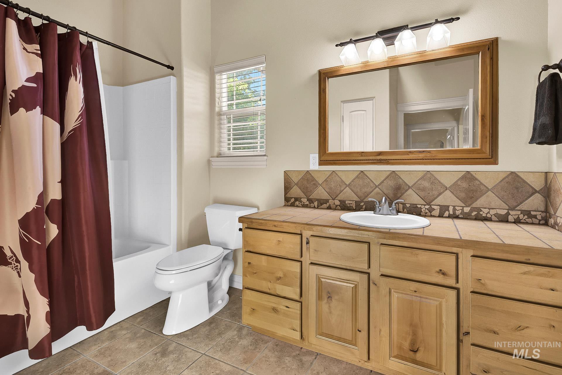 27114 Lower Pleasant Ridge Road Wilder, ID 83676 - Photo 41 of 48 Full bath featuring vanity, tasteful backsplash, tile patterned flooring, and shower / tub combo with curtain