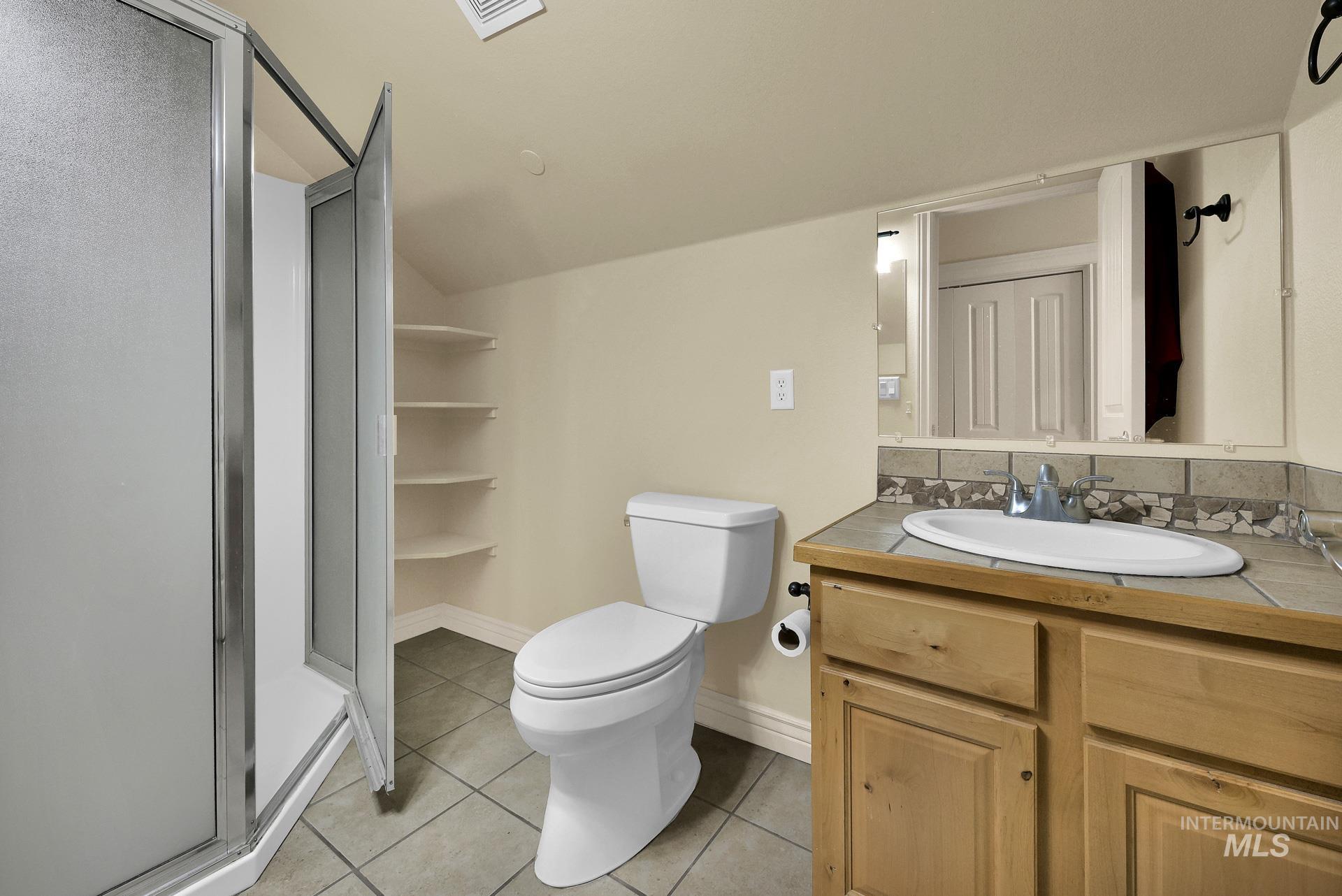 27114 Lower Pleasant Ridge Road Wilder, ID 83676 - Photo 44 of 48 Full bath with tile patterned flooring, a stall shower, vanity, and lofted ceiling