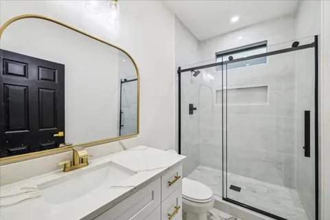 a bathroom with a shower sink vanity mirror and toilet