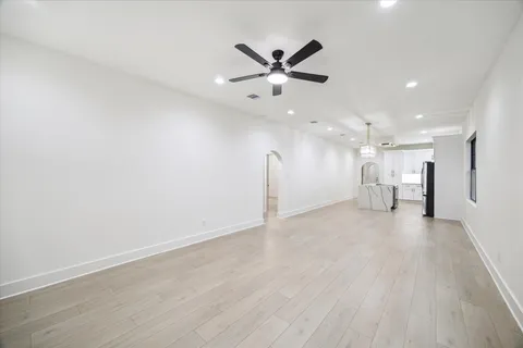 a view of an empty room with a ceiling fan and wooden floor