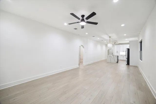 a view of an empty room with a ceiling fan and wooden floor