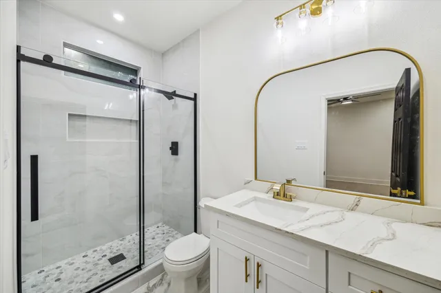 a bathroom with a granite countertop sink toilet and shower