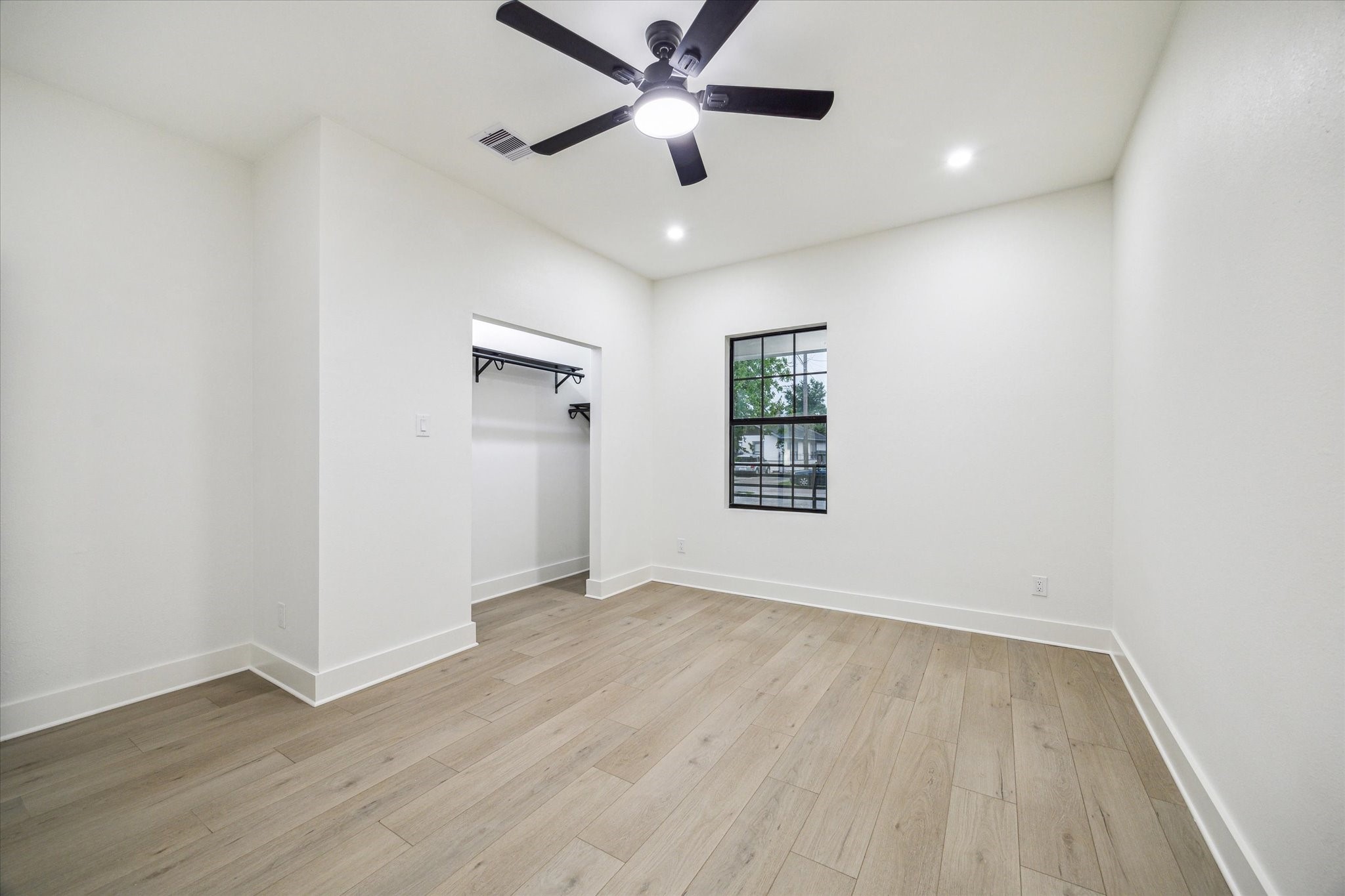 228 Lenox Street Houston, TX 77011 - Photo 10 of 16 an empty room with wooden floor ceiling fan and windows