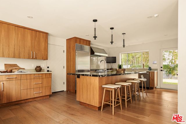 a kitchen with stainless steel appliances granite countertop a stove top oven a sink a dining table and chairs with wooden floor