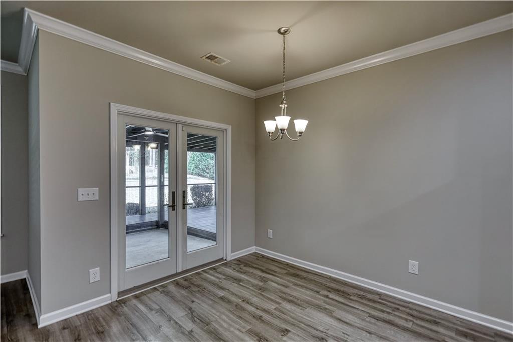 325 Tarpley Way Covington, GA 30016 - Photo 12 of 62 en empty room with wooden floor chandelier and glass door