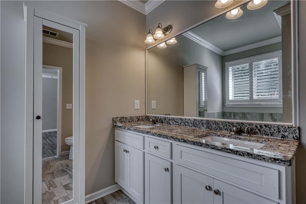 325 Tarpley Way Covington, GA 30016 - Photo 21 of 62 a bathroom with a granite countertop sink a large mirror and a vanity