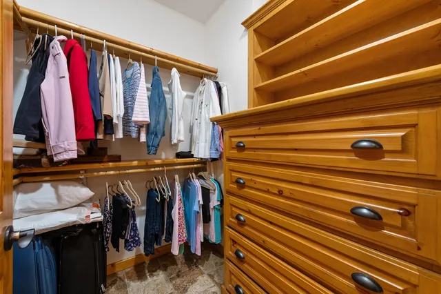 a view of walk in closet with clothes and shoes