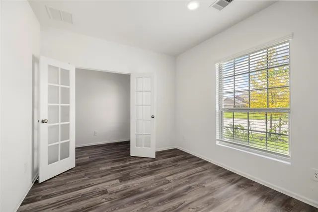 an empty room with wooden floor and windows