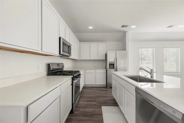 a kitchen with stainless steel appliances granite countertop a sink a stove and a refrigerator
