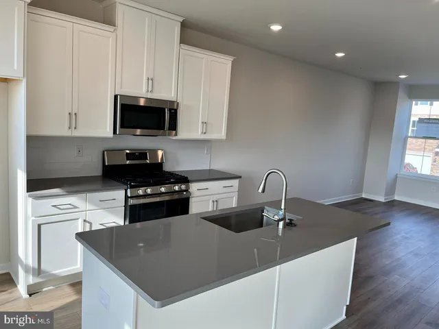 a kitchen with stainless steel appliances granite countertop a sink a stove top oven a counter space and cabinets